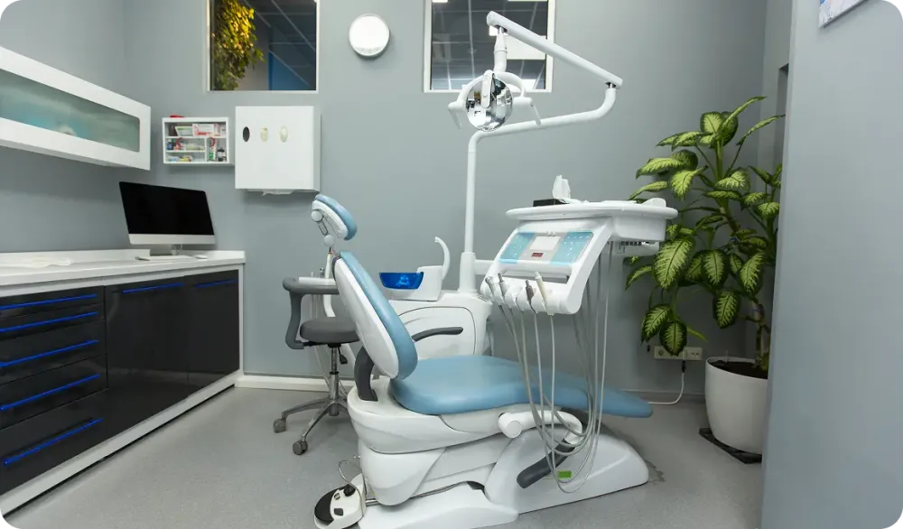 Modern dental office with a comfortable treatment chair, decorative plants, and framed artwork for a relaxing patient experience.