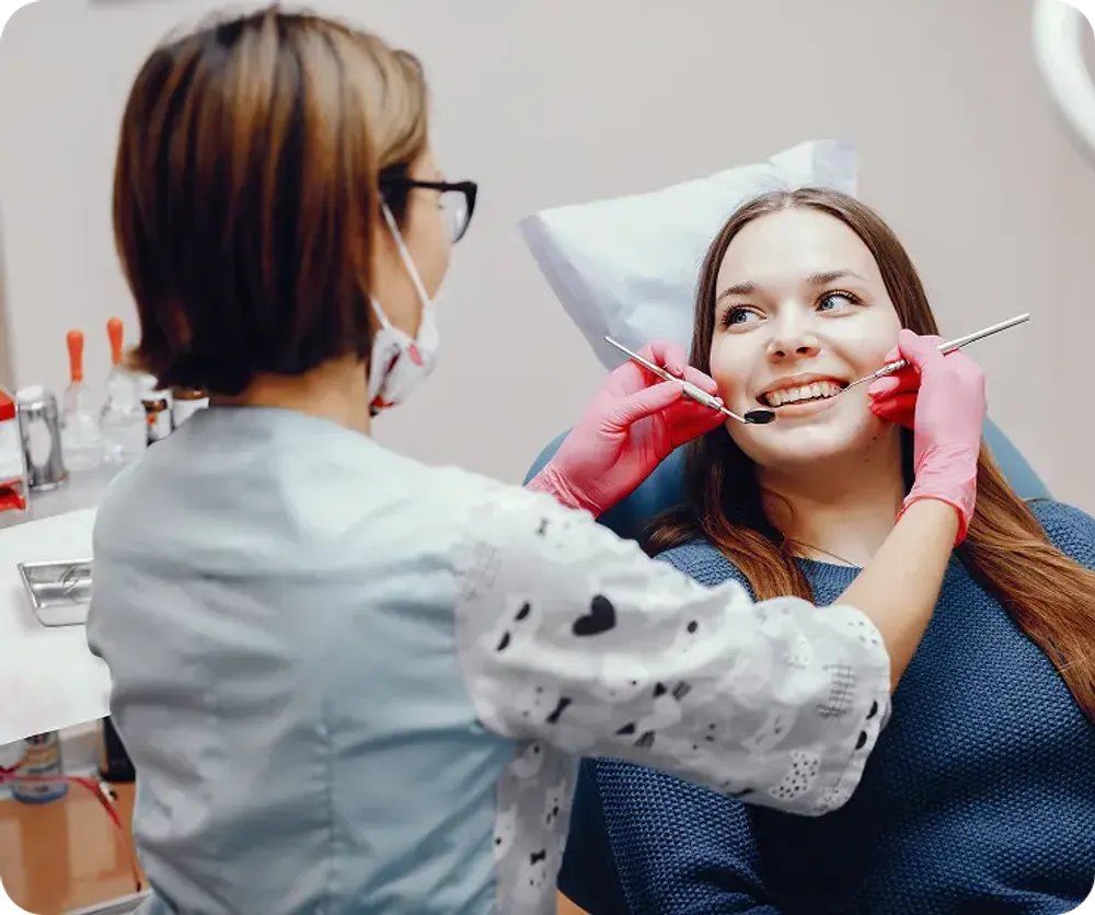 A female dentist performing a dental check-up on a happy patient, using professional tools.