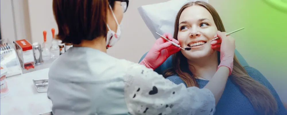 A female dentist performing a dental check-up on a happy patient, using professional tools.