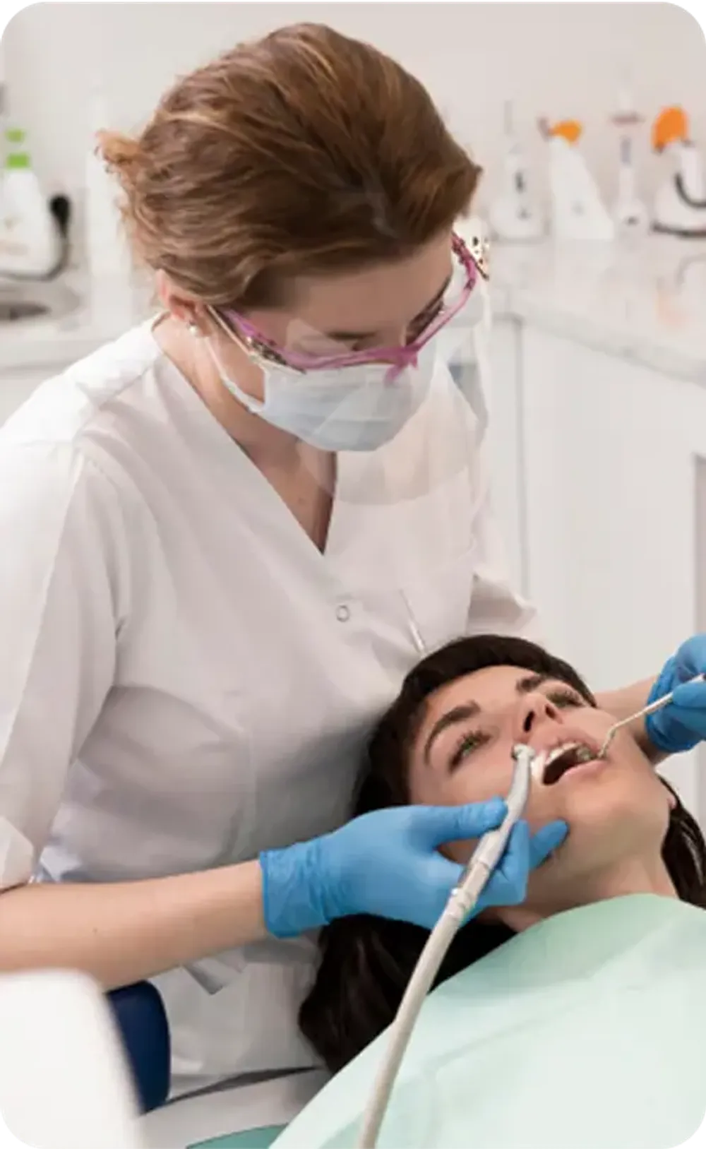 Female dentist wearing a face mask performing a dental procedure on a patient.