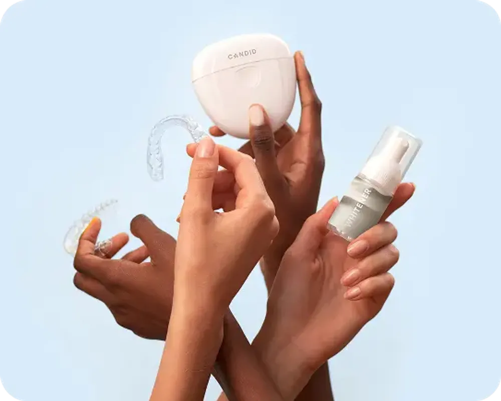 Three hands each holding a different dental care product.