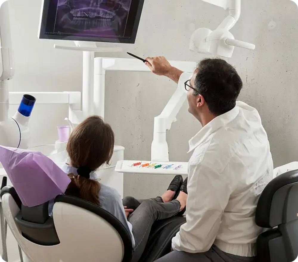 A man and a woman seated in a dentist chair, both appearing relaxed during a dental appointment.