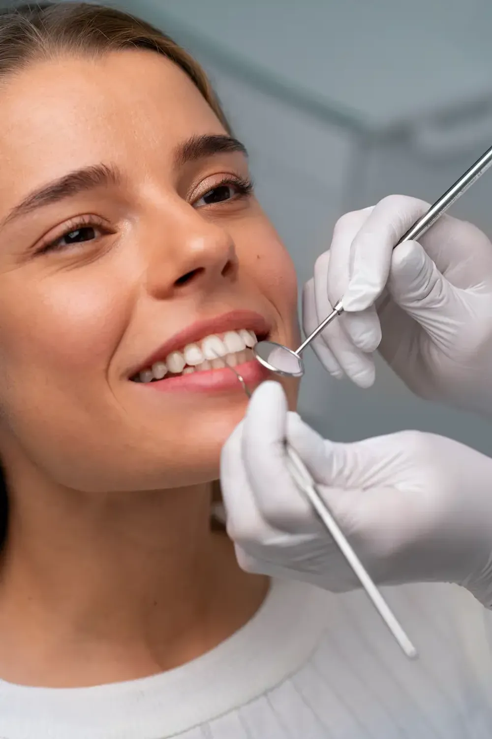 Dental instruments performing a smile design procedure on a woman's teeth, showcasing cosmetic dentistry for a brighter, aligned smile.