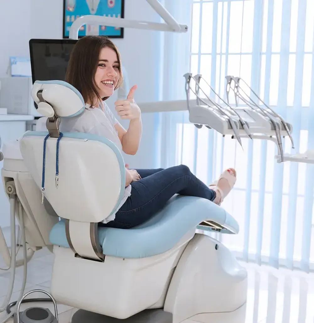 smiling female patient sitting chair showing thumb up dental clinic