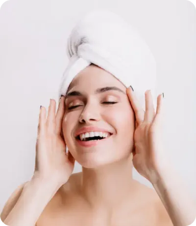 Smiling women with hands in her face and a towel in her head.webp