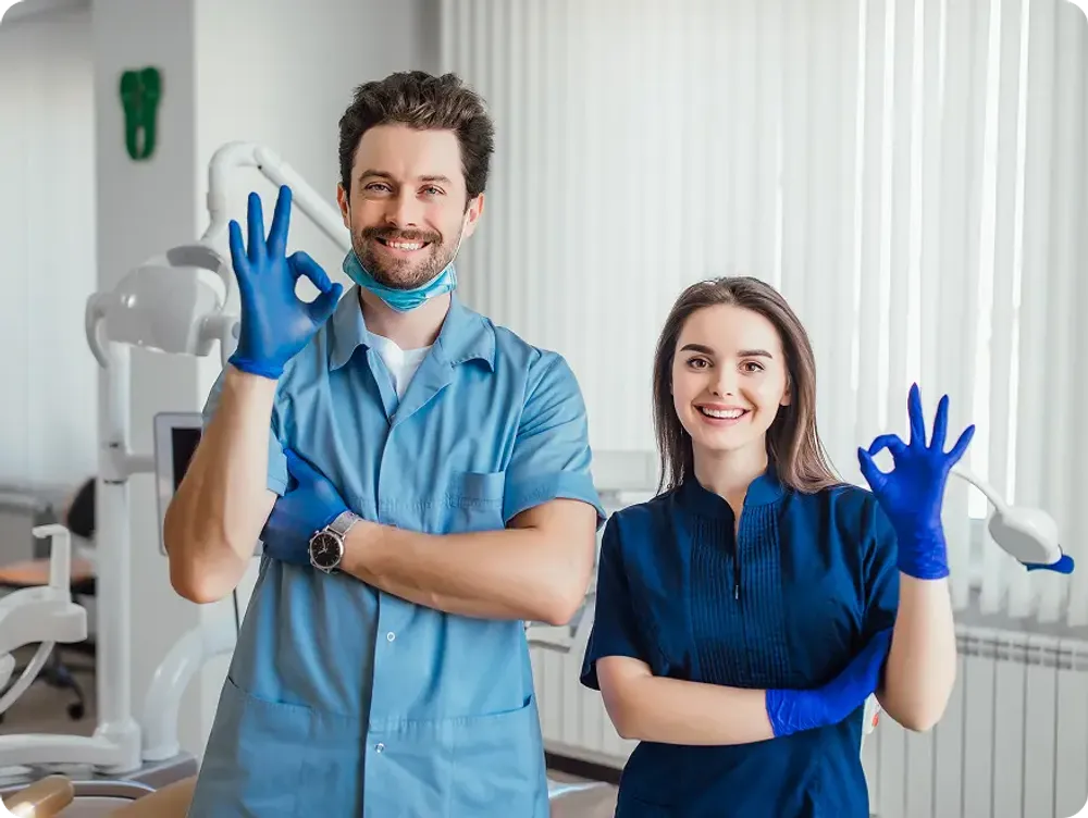 Male and female dentists smiling and giving a thumbs-up gesture