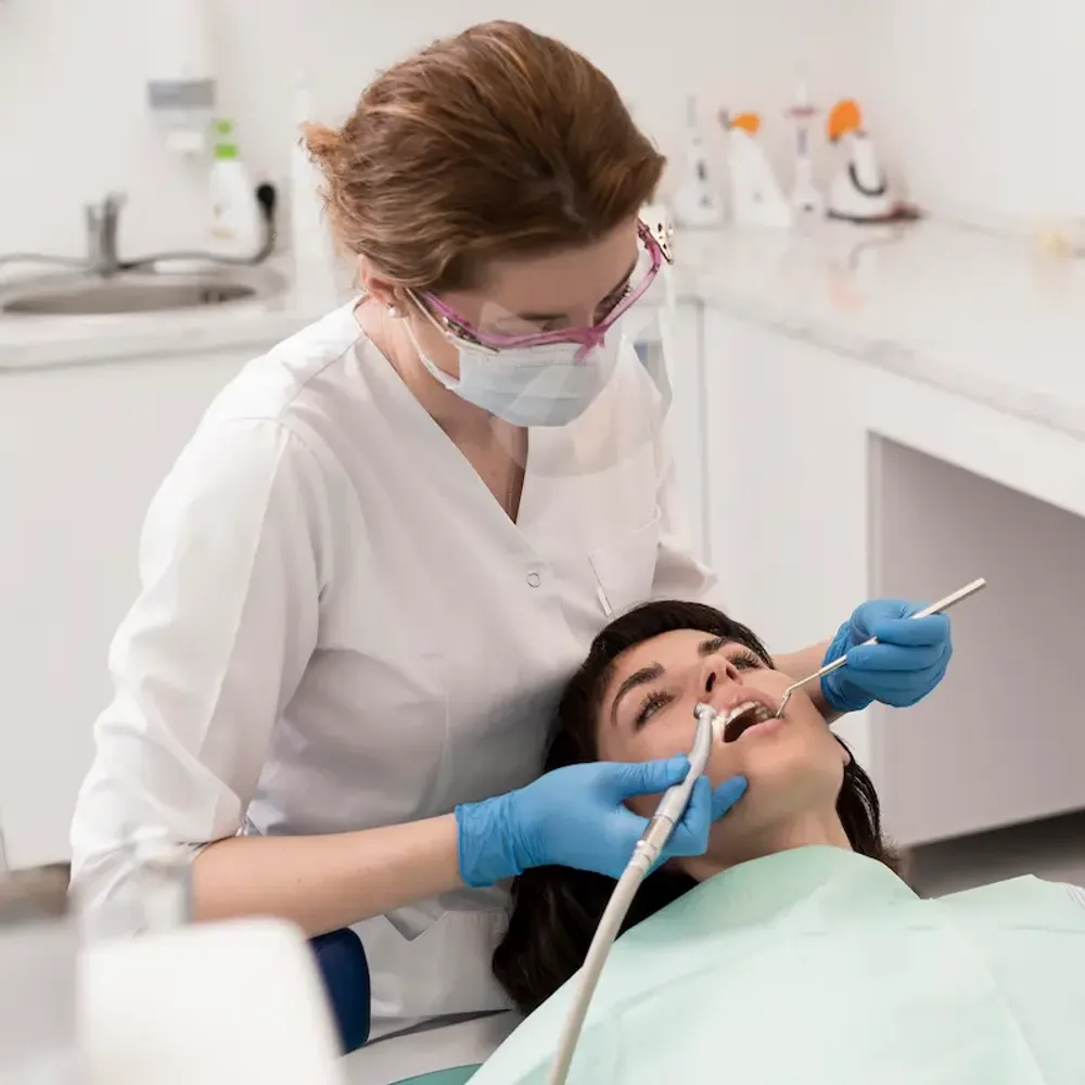Dentist's hands adjusting a screw on a dental prosthesis with precision tools, performing denture repair or implant maintenance.